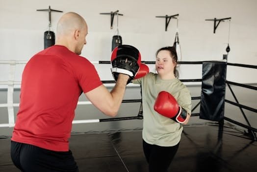 A woman with Down syndrome trains with a bald boxing coach in a gym.