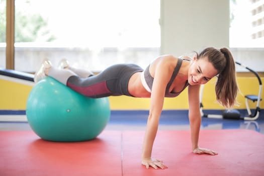 Active woman performing a workout with a stability ball indoors, showcasing fitness and strength.