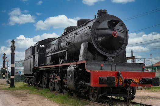 Historic black steam locomotive on tracks in Alcázar de San Juan, Spain.