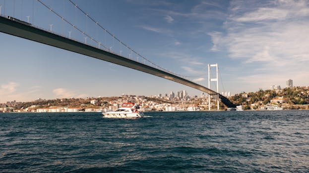 A stunning view of the Bosphorus Bridge in Istanbul with a yacht cruising the waters on a clear day.