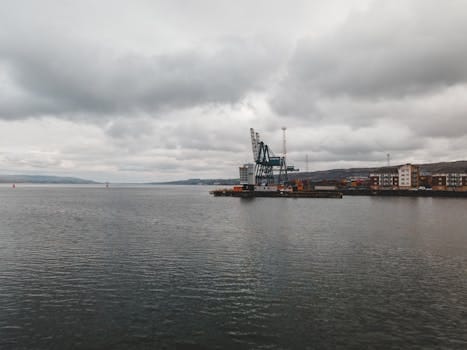 A serene harbor view in Scotland featuring cranes and an overcast sky, perfect for industrial themes.