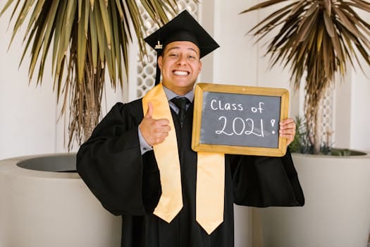 Cheerful young graduate in cap and gown holding Class of 2021 sign with thumbs up.
