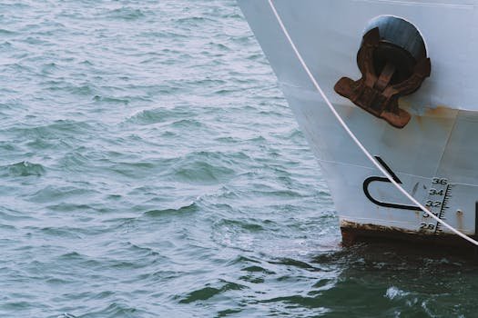 A detailed view of a ship's bow and anchor slicing through vibrant aqua waves.
