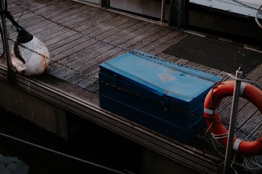 A vibrant wooden dock featuring a lifebuoy and a blue box, ideal for maritime themes.