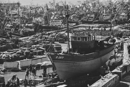 Black and white photo of a bustling shipyard in Essaouira, Morocco, showcasing fishing boats.