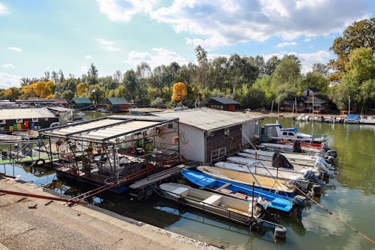 Houseboats and small boats moored along a tranquil river under a bright blue sky.