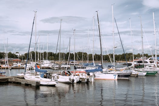 Viața la Bord în 2026: Sfaturi Esențiale, Cursuri Online de TOP și Joburi Căutate pentru Navigatori! 4 A peaceful marina with yachts and sailboats moored under a cloudy sky, ideal for enthusiasts.