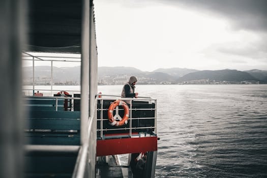 Ghid complet pentru obținerea certificatului STCW: pași și avantaje 3 A lone traveler on a ferry enjoys a peaceful ride with breathtaking mountain views.