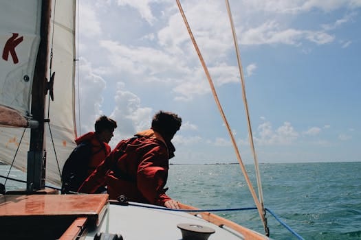 Two sailors on a sailboat enjoying a sunny day on the ocean.