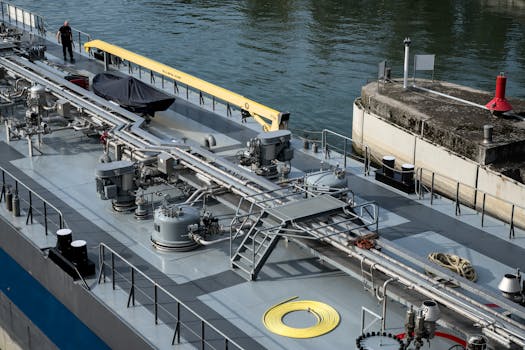 Analiza Costurilor și Beneficiilor Cursului STCW Basic Safety Training Online 4 A detailed view of an industrial ship docked at a harbor with visible engineering components.