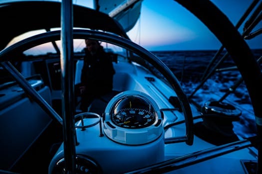 Close-up of sailboat steering wheel and compass during twilight navigation.