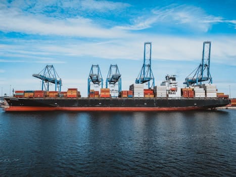 Large cargo ship with colorful metal containers floating on rippling water of ocean under cloudy blue sky in daylight