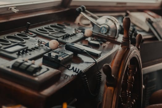 Cum să Navighezi pe Timp de Noapte: Curs Radar ARPA pentru Siguranța Navigatorilor 2 Vintage boat control panel with various gadgets and a wooden steering wheel.