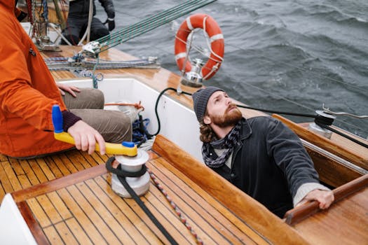 Pași pentru a Obține Certificat Marinar Vreme Rea și Sfaturi de Pregătire 3 Two sailors navigating a wooden yacht on open waters, showcasing teamwork and adventure.
