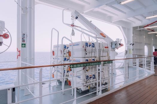 Cum să Alegi Eficient Cursul Operator GMDSS în România: Sfaturi și Costuri 2026 4 Cruise ship deck with lifeboats and safety equipment overlooking the serene ocean.