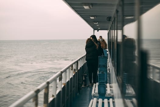 Cum să Alegi Între Școală Maritimă Internațională sau Locală pentru Certificatul STCW 2 A group on a ferry boat appreciating the tranquil ocean view under a cloudy sky.
