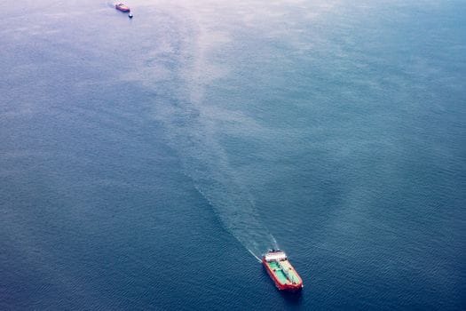 Cum să Alegi Între Școală Maritimă Internațională sau Locală pentru Certificatul STCW 4 Two cargo ships navigate the vast blue ocean, showcasing maritime transport.