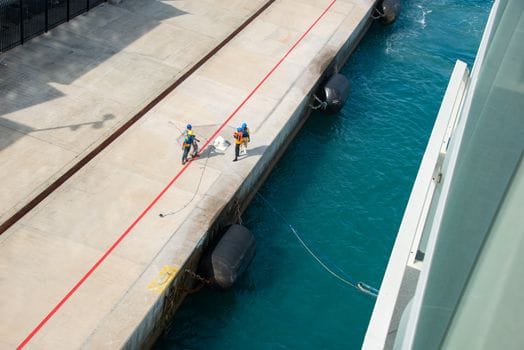 Cum să Alegi un Curs Maritim Distanță Acreditat: Tutorial Detaliat pentru Navigatorii Români 4 High angle view of workers preparing a vessel for docking at a sunlit pier.