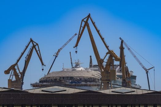 Cum să Compari Contractele de Muncă ale Navigatorilor: Ofițer Punte vs Ofițer Mașină 2 Scenic view of shipyard cranes surrounding a cruise ship under a clear blue sky in Cádiz, Spain.