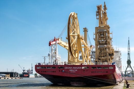 Cum să Compari Contractele de Muncă ale Navigatorilor: Ofițer Punte vs Ofițer Mașină 4 The Ceona Amazon vessel docked at Bremerhaven's bustling harbor on a sunny day.
