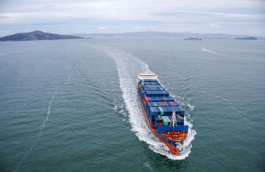 Cum să Crești Șansele de Angajare prin Curs Avansat Supraviețuire pe Mare Complet 3 Aerial view of a large container ship sailing through open ocean waters.