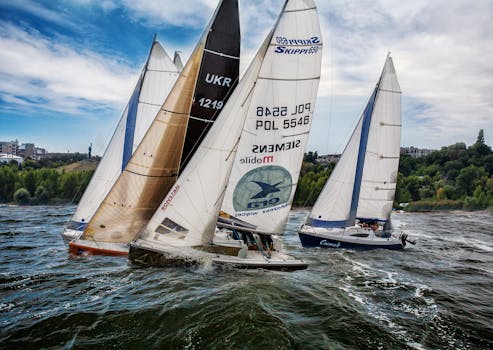 Dynamic sailboat race on a lake with vibrant sails against a clear blue sky.