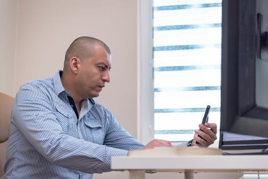 Cum să Optimizezi Siguranța Cargo Containere cu Cursuri Maritime Specializate 3 Adult trader engaged with smartphone and monitor in an office setting.