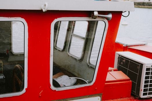 Cursuri Online RYA Navigație și Securitate vs Opțiuni Tradiționale: Ghid Complet pentru Certificare 3 Detailed image of a red boat cabin showing windows and equipment by the water.