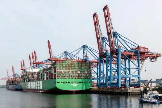Container ship in Hamburg harbour with large cranes and shipping containers.