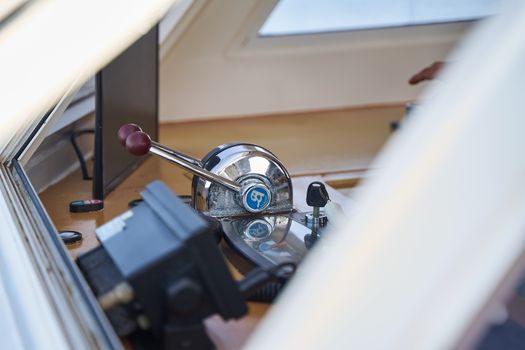 Detailed view of boat control levers with shiny metal finish and window reflections.