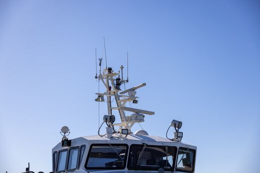 Detailed view of a modern boat's radar and aerial equipment with clear blue sky background.