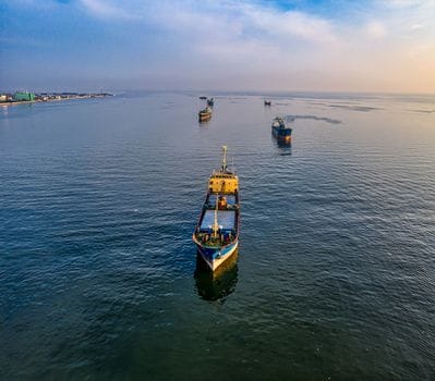 Adevărul despre Educatia Maritimă Online: De ce Nu Este Întotdeauna Răspunsul pentru Cariera ta pe Mare în România 3 An aerial view of multiple cargo ships navigating the waters near Jakarta, Indonesia.
