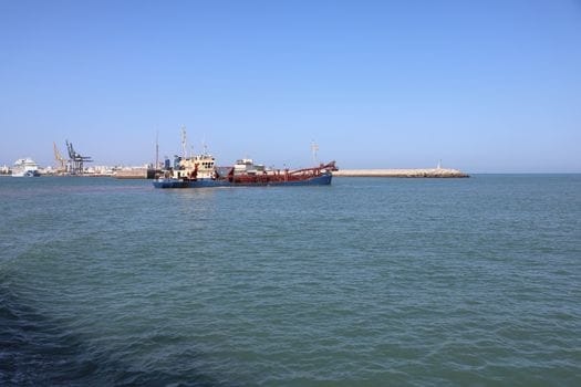 Adevărul despre Educatia Maritimă Online: De ce Nu Este Întotdeauna Răspunsul pentru Cariera ta pe Mare în România 4 Scenic view of a dredger in Cádiz port, Spain, showcasing maritime activity on a clear day.