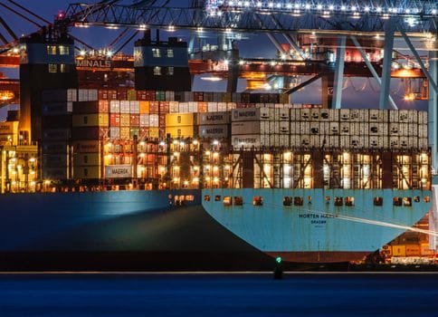 Care sunt avantajele certificărilor STCW în România în 2026 pentru ofițerii maritimi? 2 A lit cargo ship loaded with containers docked at Gothenburg harbor, showcasing the bustling night operations.