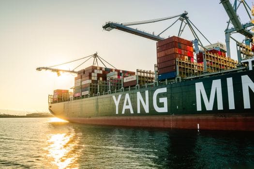 Care sunt avantajele certificărilor STCW în România în 2026 pentru ofițerii maritimi? 3 Large cargo ship with stacked containers and cranes at sunset in a harbor.