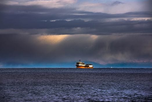 Cât de Pregătiți Sunt Ofițerii de Punte Recenți din România pentru Piața Muncii Maritimă în 2026? 3 A solitary ship navigates the vast ocean under dramatic, stormy clouds at sea.