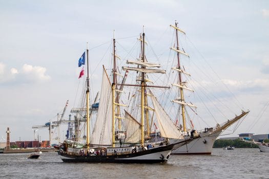 Ce Schimbări Legislative din 2026 Influentează Certificările STCW în România? 2 Majestic tall ships with large sails in Hamburg's port on the Elbe River.