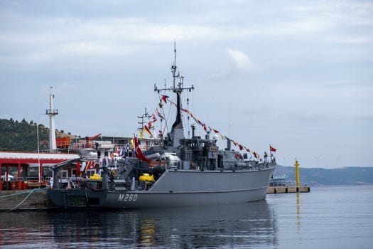 Ce Schimbări Legislative din 2026 Influentează Certificările STCW în România? 3 A decorated naval ship, identified by M260, docked in a serene harbor.