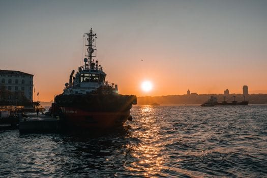 Ce Schimbări Legislative din 2026 Influentează Certificările STCW în România? 4 A stunning sunrise over Bosphorus Strait in Istanbul with a prominent tugboat and calm waters.