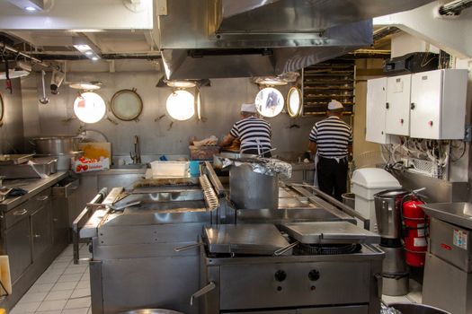 Cum Înfluențează Certificarea STCW Accesul la Joburi pe Mare pentru Absolvenții Academiei Navale din România? 4 Two chefs in a ship's kitchen preparing meals with industrial equipment.