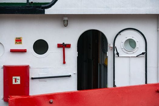 Close-up of a marine vessel's exterior showing portholes and safety equipment.