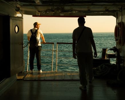 Cum să alegi corect cursurile STCW pentru o carieră de succes pe mare 3 Two men standing on a ship deck, enjoying a sunset over the ocean.