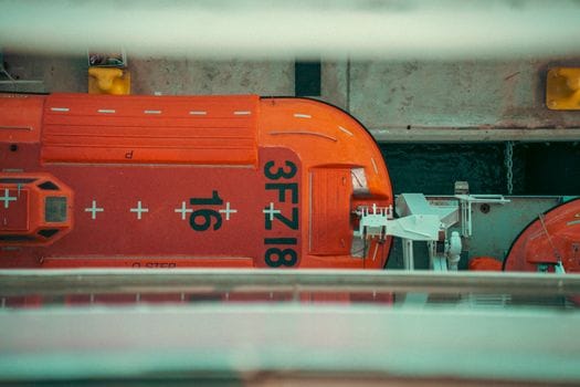 Top-down view of two orange lifeboats, marked '3FZ18', docked on a ship, Spain.