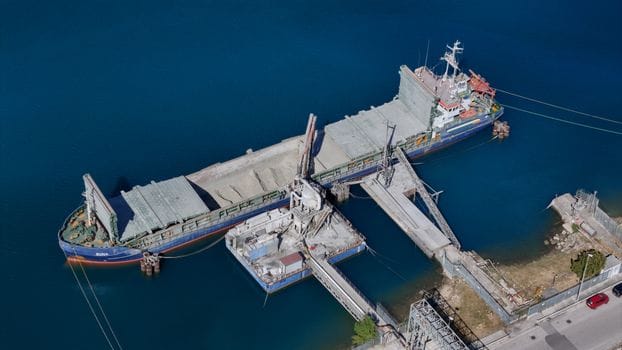 Opportunity Learning vs Inscrieri la Academia Navală: Alegerea Ideală pentru Cariera ta Maritimă în 2026? 4 An aerial view of a cargo ship docked at an industrial loading facility, showcasing maritime transportation.