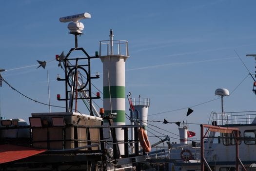 Pașii esențiali pentru obținerea certificatului STCW 3 Detailed view of maritime equipment and antennas at Foça Harbor, İzmir with clear blue sky.