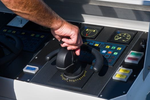 Pașii esențiali pentru obținerea certificatului STCW 4 A close-up view of a hand managing a boat's control panel, emphasizing precision and control.