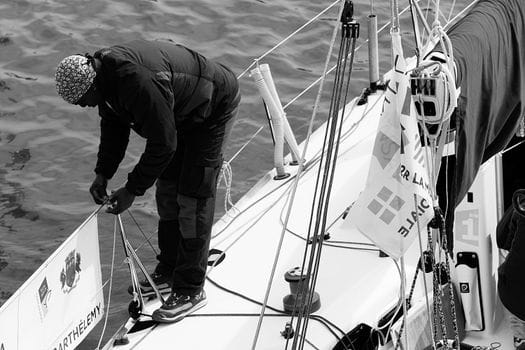 Man working with ropes on a sailboat, showcasing nautical skills and maritime leisure.
