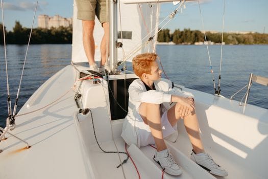 Top 5 Inițiative de Educație Maritimă care Transformă Cariera pe Mare în România, Vară 2026 2 A young man relaxes on a sailboat, enjoying a sunny day on the water with scenic views.