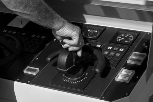 Top 7 Reglementări IMO care Transformă Educația Maritimă în România în Iulie 2026 3 Black and white image of a person's hand adjusting a throttle lever on a boat control panel.