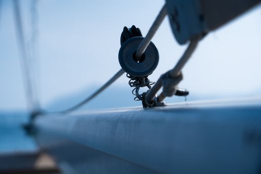 Minimalist shot of sailboat rigging with focus on pulley and rope, set against tranquil ocean backdrop.